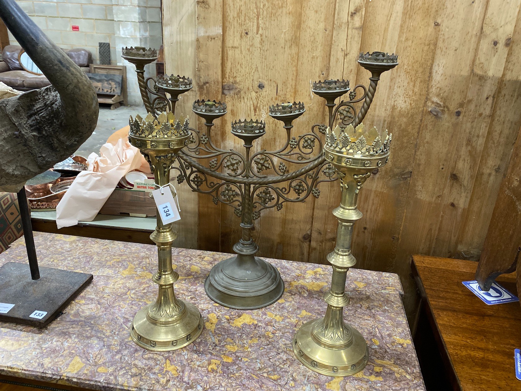 Two brass Gothic style pricket candlesticks, largest height 62cm and a brass Menorah candlestand